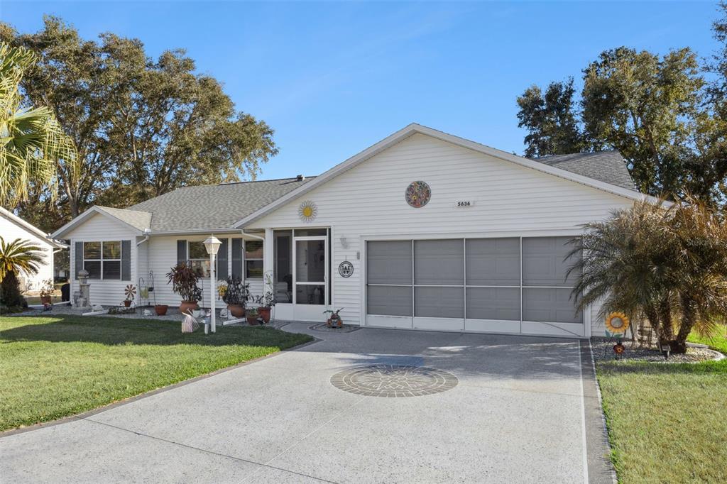 A single-story house with white siding, a screened garage door, and a concrete driveway — 5636 LAVER STREET, LEESBURG, FL