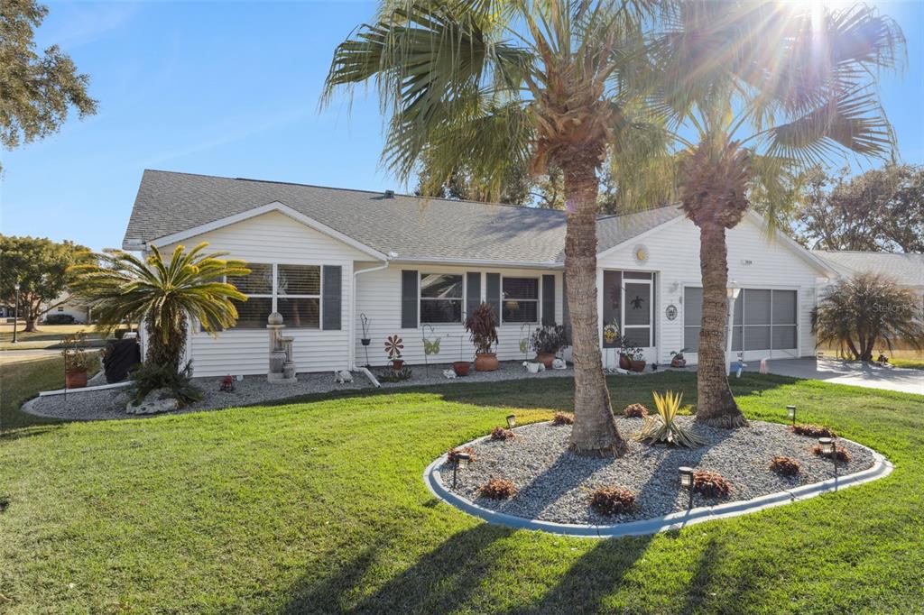 A single-story white house with a gray shingled roof, palm trees, and a gravel garden — 5636 LAVER STREET, LEESBURG, FL