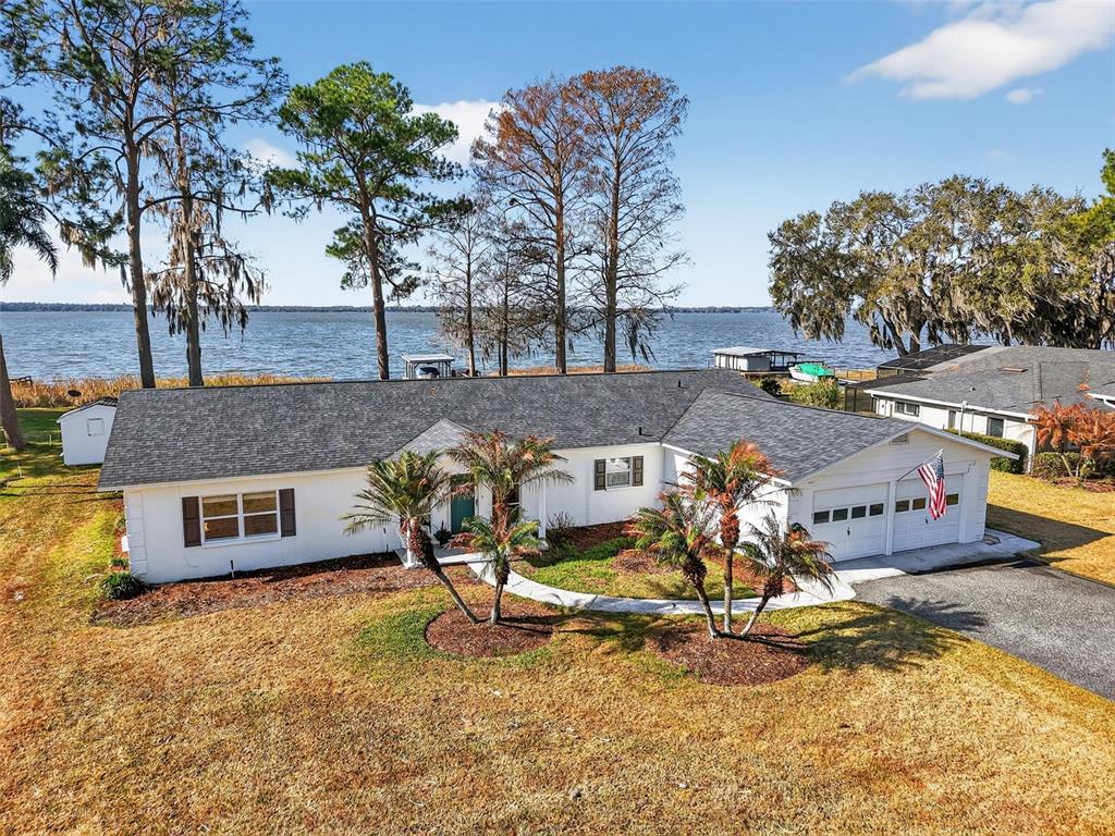 A wooden deck overlooks a lake at sunset with two red chairs and a lounge chair — 33225 LAKESHORE DRIVE, TAVARES, FL