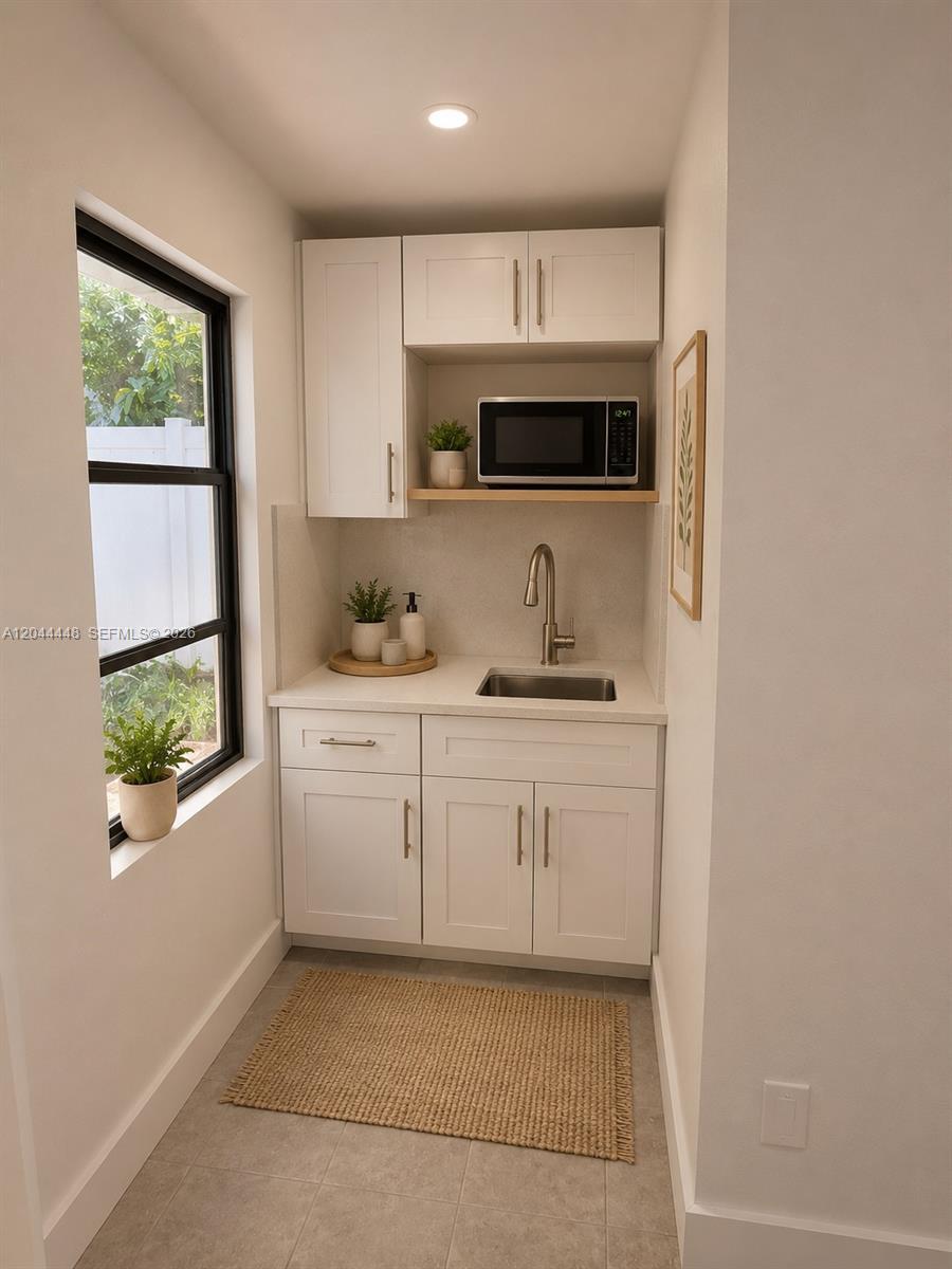 A small kitchenette features white cabinets, a stainless steel sink, and a built-in microwave — NORTH MIAMI BEACH, FL