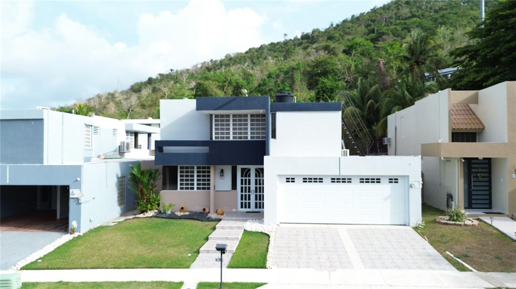 A two-story house with a white garage, blue accents, and a front lawn — Estancias de Bairoa CALLE MIRAMELINDA, CAGUAS, PR
