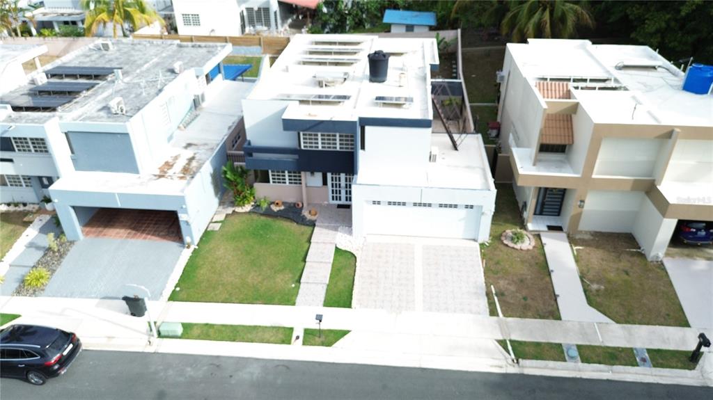 An aerial view shows three modern suburban houses with driveways, lawns, and flat roofs — Estancias de Bairoa CALLE MIRAMELINDA, CAGUAS, PR