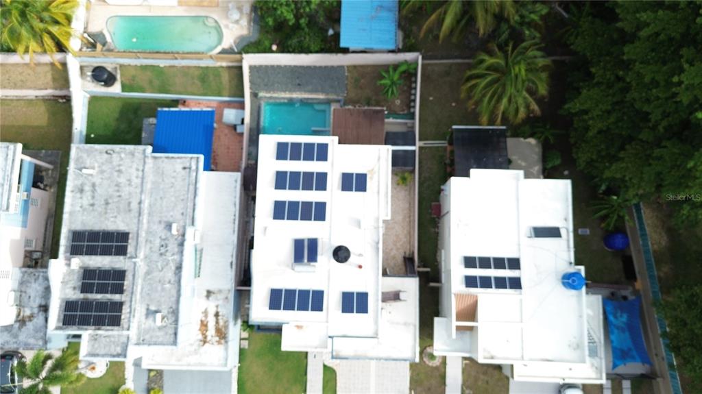 An aerial view shows three adjacent houses with flat roofs, solar panels, and swimming pools — Estancias de Bairoa CALLE MIRAMELINDA, CAGUAS, PR