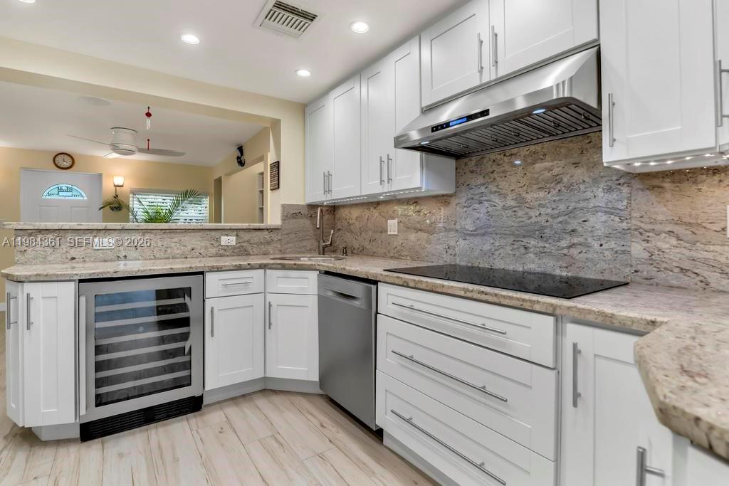 A kitchen features white cabinets, granite countertops, a stainless steel range hood, and a wine cooler — 222 SW 7th St, Dania Beach FL 33004, DANIA BEACH, FL