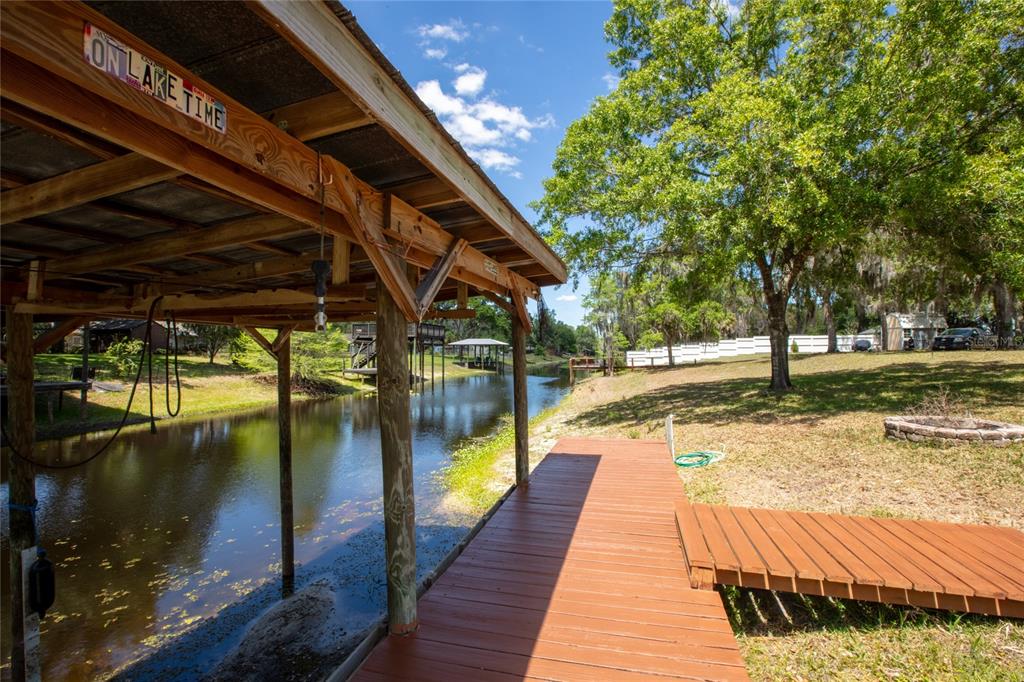 A wooden dock with a covered boat slip extends over a narrow canal — 5930 ISLAND ROAD, MELROSE, FL
