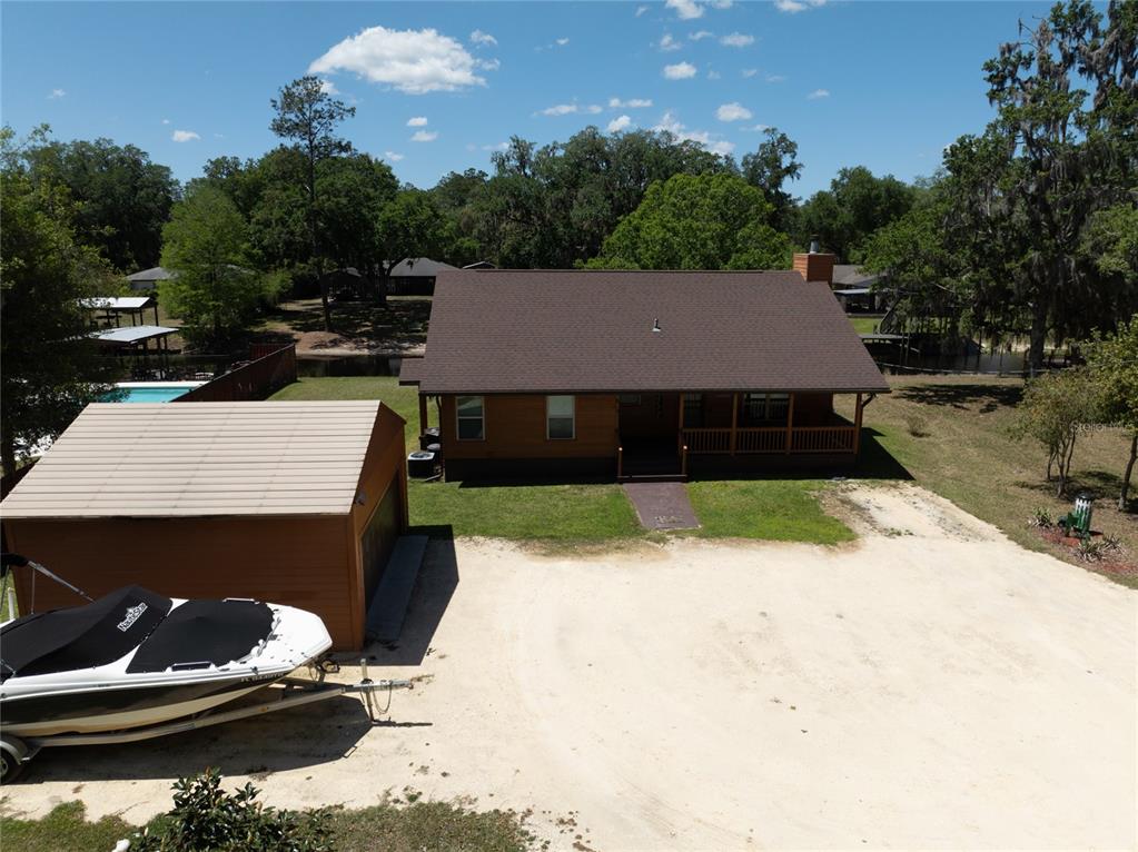 An aerial view shows a wooden house with a brown roof, a detached garage, and a boat — 5930 ISLAND ROAD, MELROSE, FL