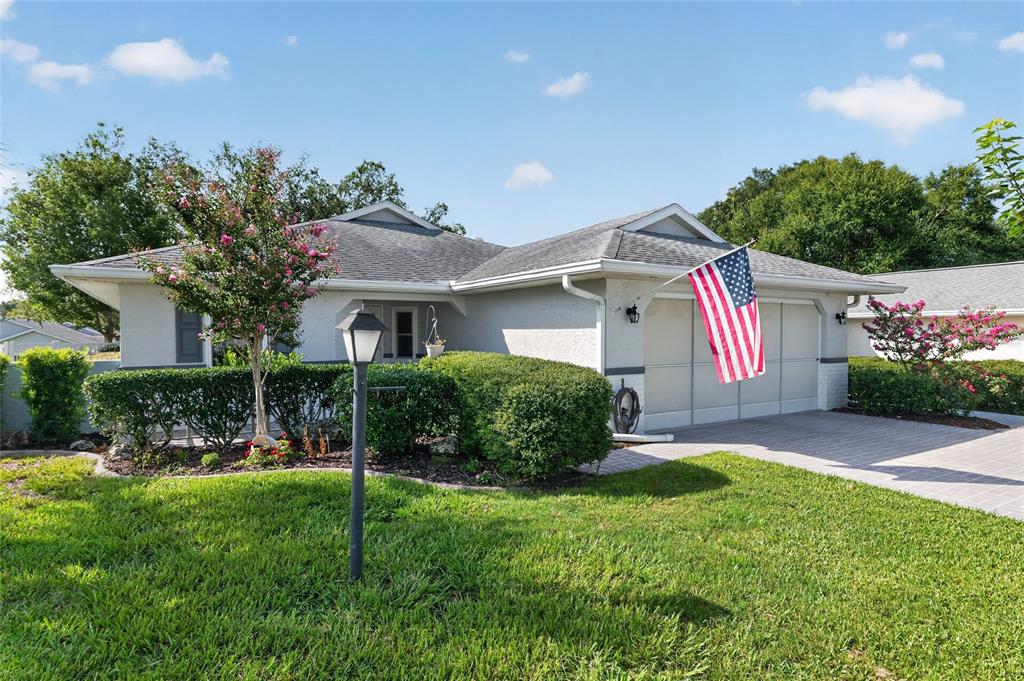 A single-story house with a gray roof, stucco exterior, and an American flag — 9153 SW 91ST TERRACE, OCALA, FL