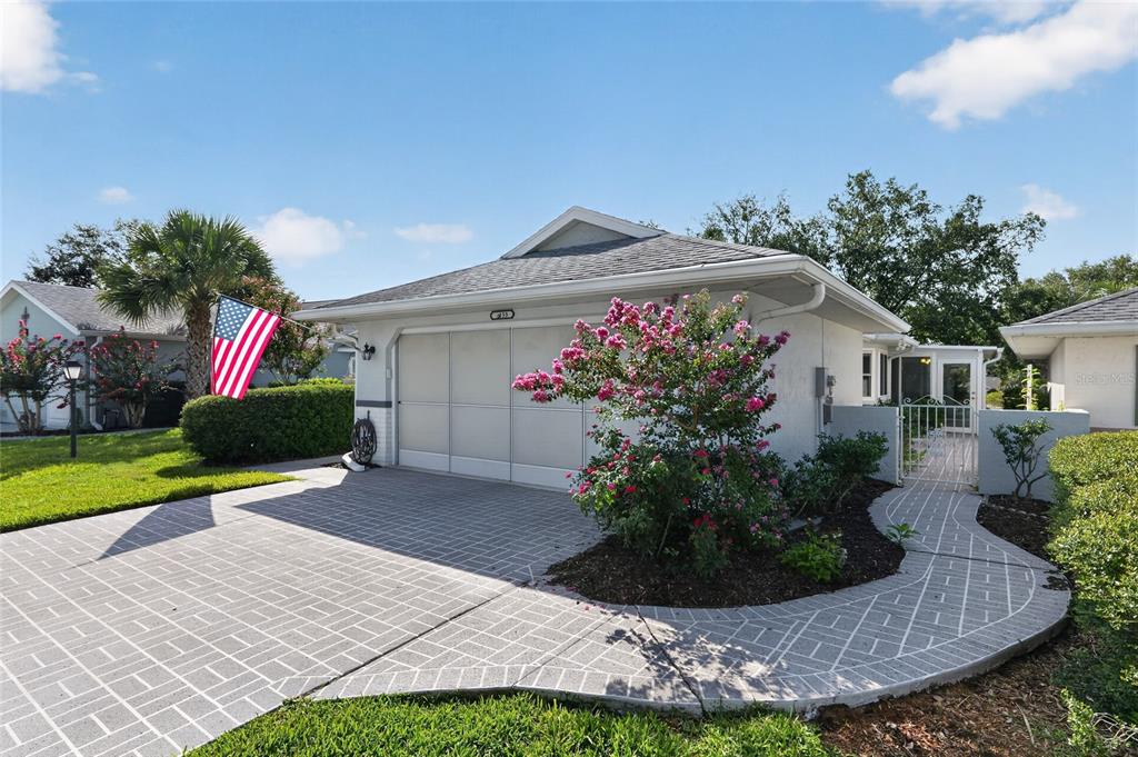 A single-story house with a gray garage, a paved driveway, and a blooming crape myrtle — 9153 SW 91ST TERRACE, OCALA, FL