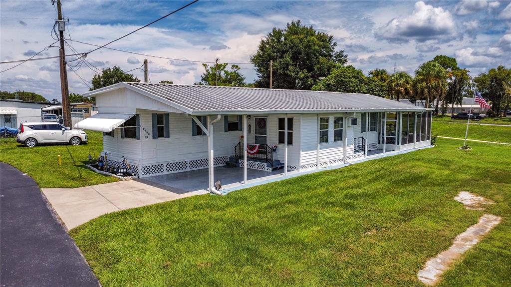 A white mobile home with a metal roof, a covered carport, and a screened-in porch — 6132 HARRIET STREET, ZEPHYRHILLS, FL