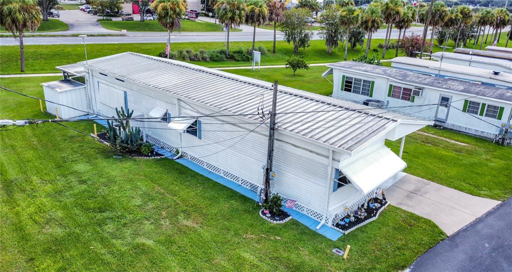An elevated exterior view of a white mobile home with a metal roof and awnings — 6132 HARRIET STREET, ZEPHYRHILLS, FL