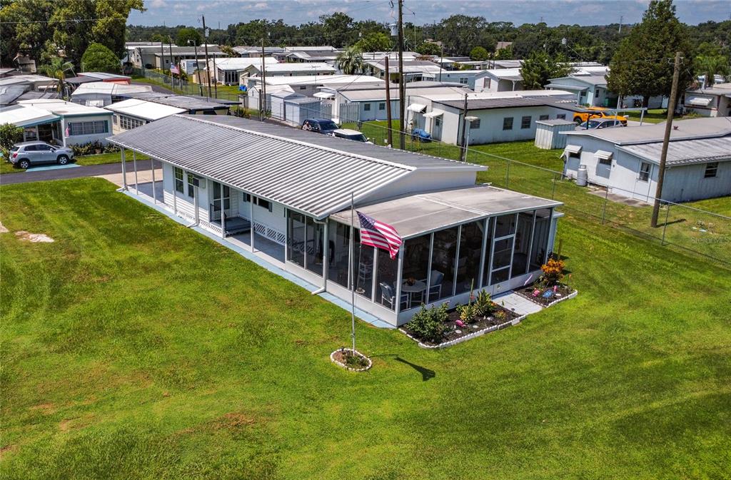 An aerial view of a white mobile home with a metal roof and screened-in porch — 6132 HARRIET STREET, ZEPHYRHILLS, FL