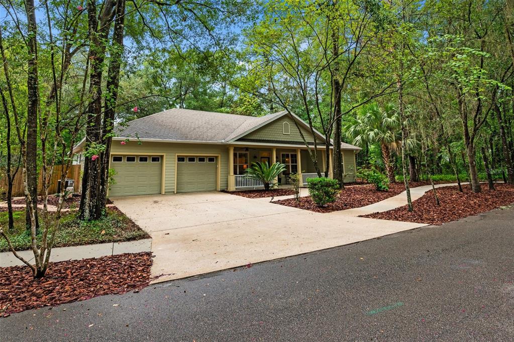 A single-story house with a two-car garage, front porch, and surrounding trees — 3883 SW 21ST DRIVE, GAINESVILLE, FL