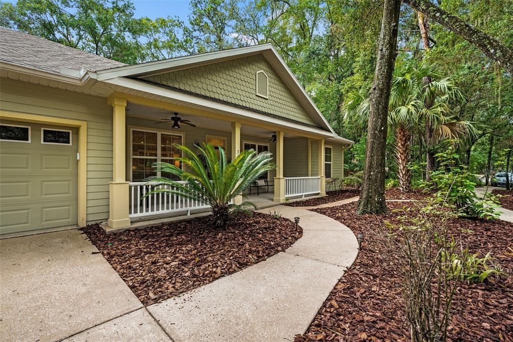 A light green house with a covered front porch, white railings, and a concrete walkway — 3883 SW 21ST DRIVE, GAINESVILLE, FL