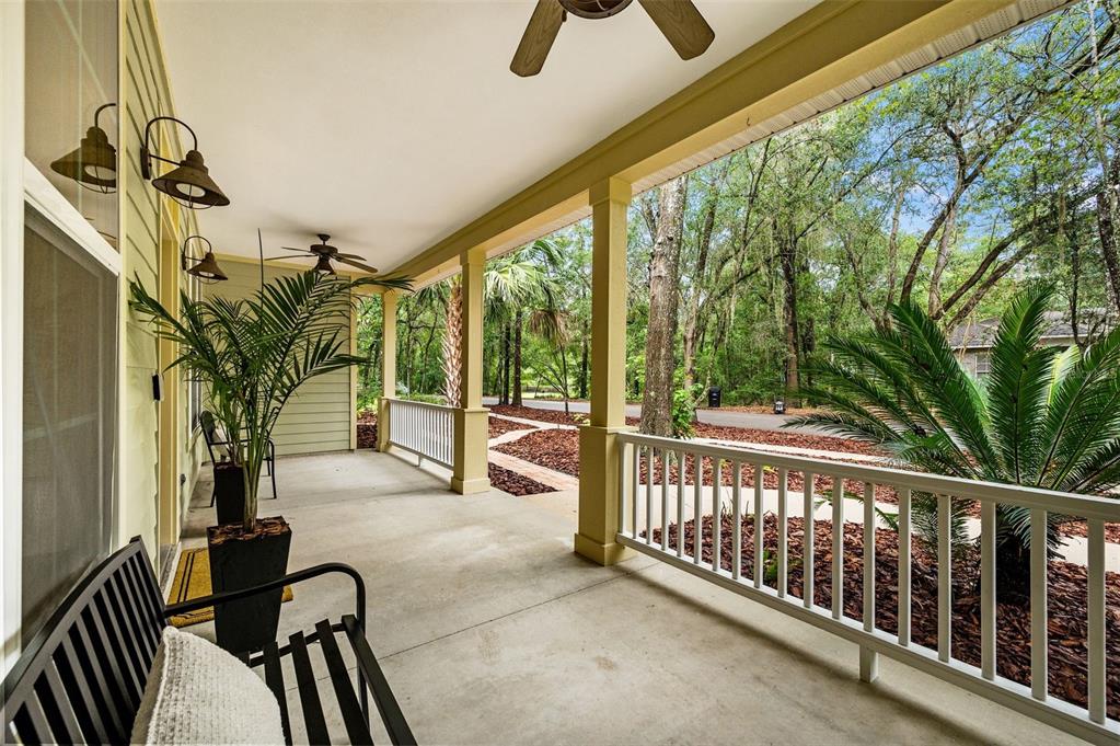 A covered porch with a concrete floor, white railings, ceiling fans, and outdoor seating — 3883 SW 21ST DRIVE, GAINESVILLE, FL