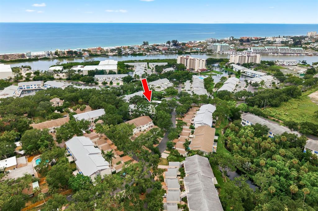 An aerial view shows a residential complex with multiple buildings surrounded by trees near water — 11440 HARBOR WAY UNIT 5013, LARGO, FL