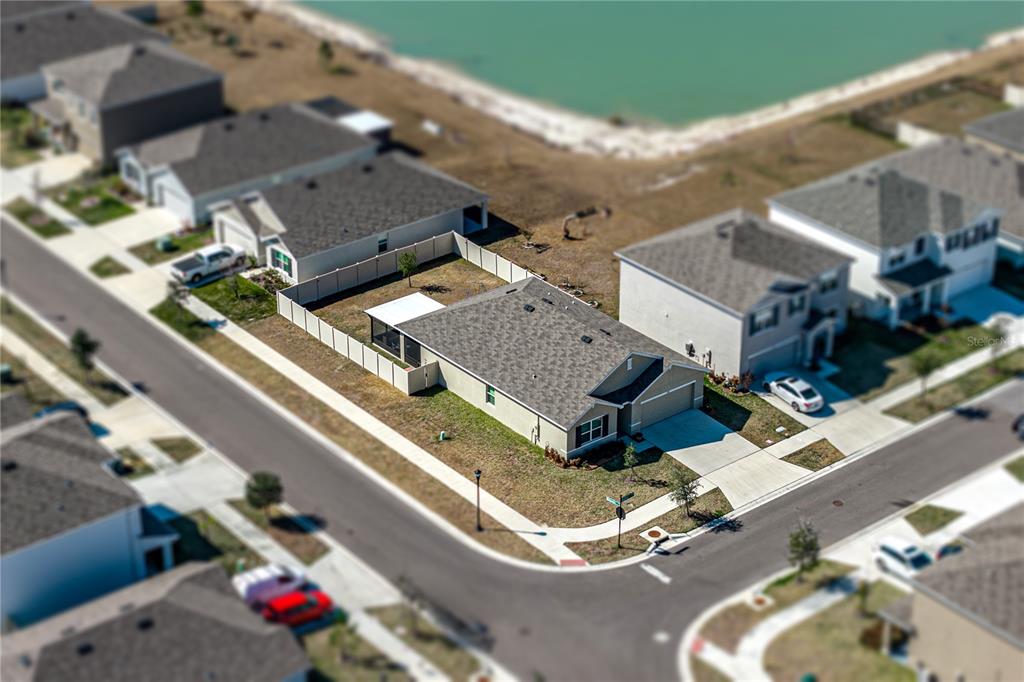An aerial view shows a suburban house with a fenced backyard near a pond — 2741 GARDINER LANE, ZEPHYRHILLS, FL