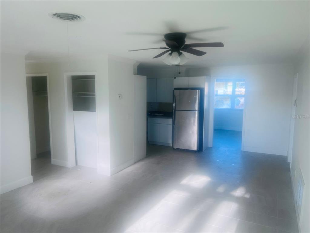 An open-concept living area features light tile flooring, a ceiling fan, and a stainless refrigerator — 323 SCOTLAND DRIVE, DAYTONA BEACH, FL