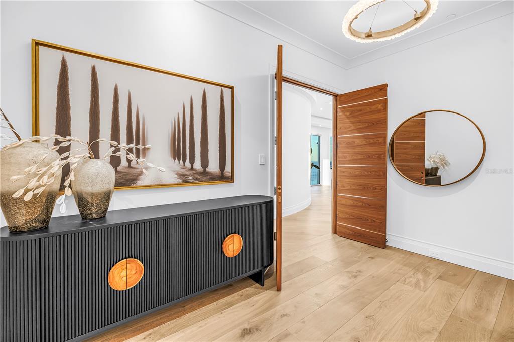 A modern entryway features a black sideboard, a landscape painting, and a wooden door — 555 5TH AVENUE NE UNIT PH1, ST PETERSBURG, FL