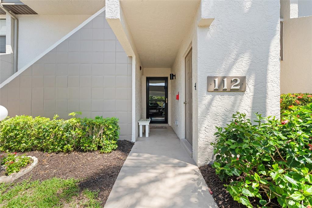A concrete walkway leads to the entrance of a residential unit marked with number 112 — 14770 EAGLE RIDGE DRIVE UNIT 112, FORT MYERS, FL