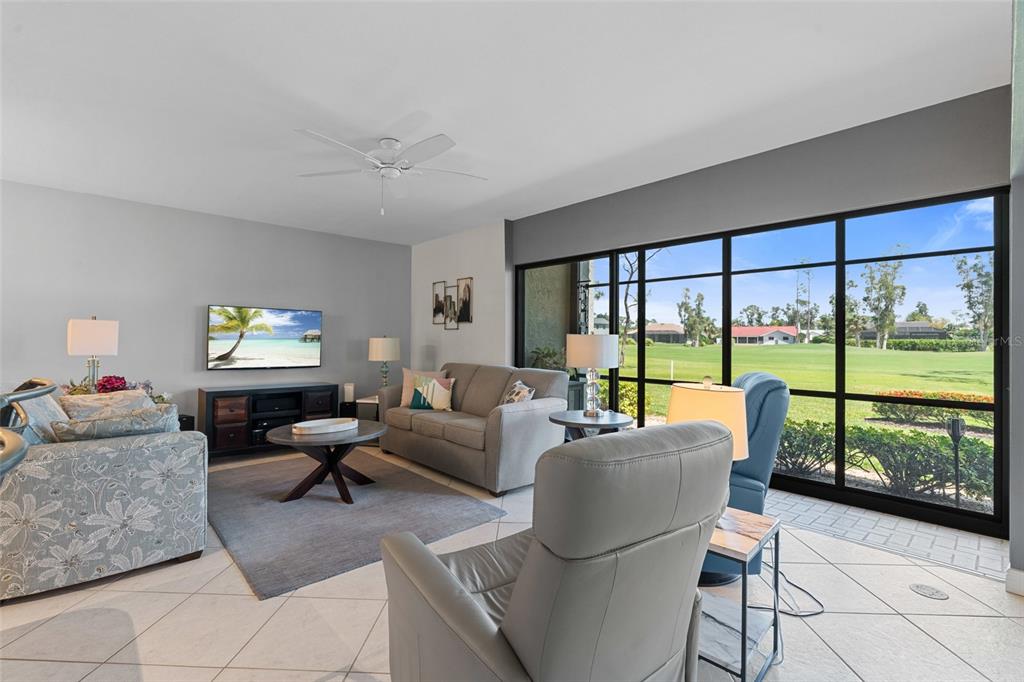 A living room features tile floors, a grey sofa, and large windows overlooking a golf course — 14770 EAGLE RIDGE DRIVE UNIT 112, FORT MYERS, FL