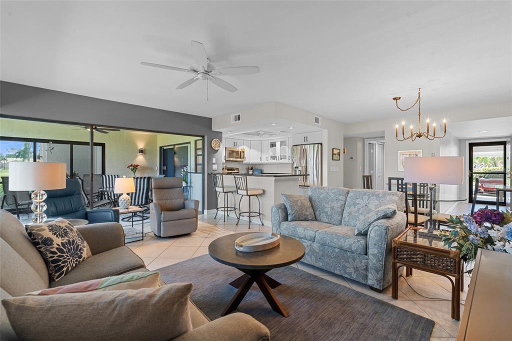 A living room with a floral sofa, round coffee table, and an open-concept kitchen — 14770 EAGLE RIDGE DRIVE UNIT 112, FORT MYERS, FL