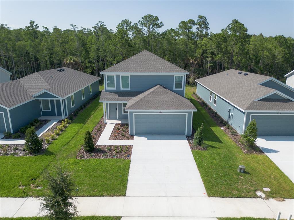 An aerial view shows a two-story blue house with a garage and a concrete driveway — 5615 MORANT BAY PATH, KISSIMMEE, FL