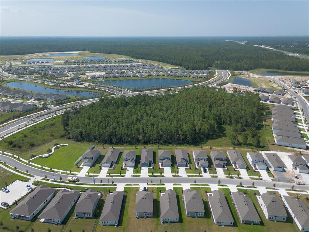 An aerial view shows a suburban neighborhood with rows of houses, ponds, and forested areas — 5615 MORANT BAY PATH, KISSIMMEE, FL