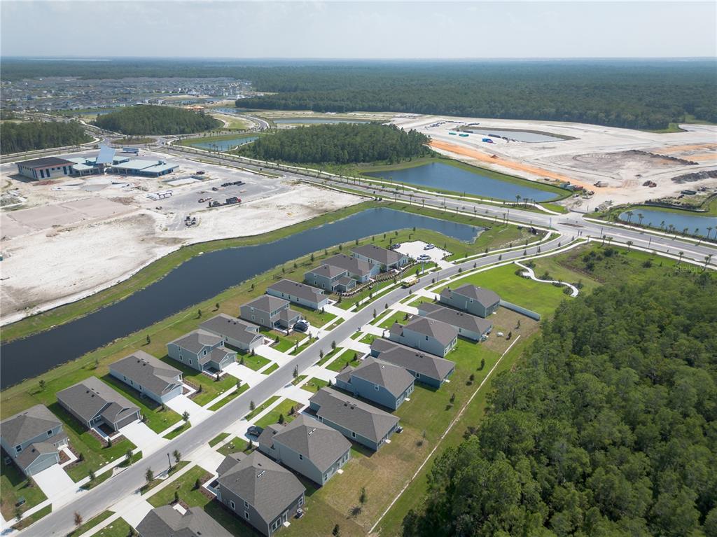 An aerial view shows a suburban neighborhood with houses, a winding road, and nearby ponds — 5615 MORANT BAY PATH, KISSIMMEE, FL
