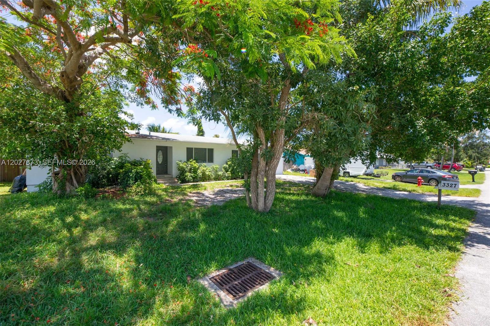 A single-story house with a white exterior is partially obscured by large trees — 3327 Sapphire Rd, Lake Worth FL 33462, LAKE WORTH, FL