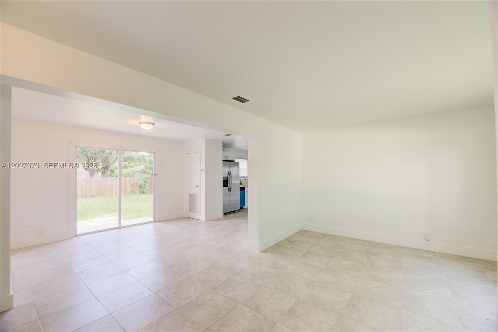 An open-concept living area features light tile flooring, white walls, and a sliding glass door — 3327 Sapphire Rd, Lake Worth FL 33462, LAKE WORTH, FL