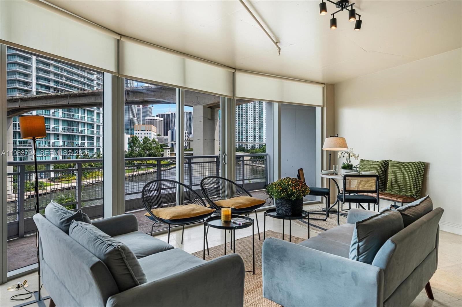 A living room with light blue sofas, modern chairs, and a balcony overlooking a city skyline — 690 SW 1st Ct # 501, Miami FL 33130, MIAMI, FL