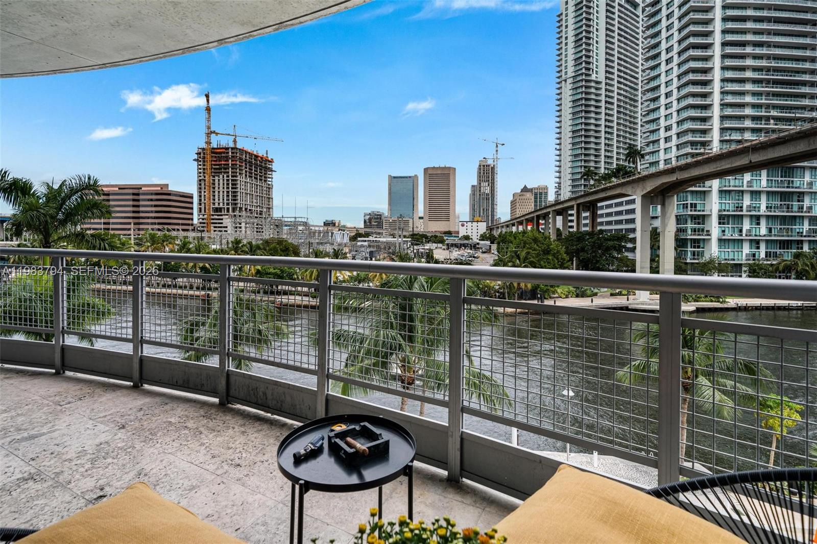 A balcony with a metal railing overlooks a river, city skyline, and construction site — 690 SW 1st Ct # 501, Miami FL 33130, MIAMI, FL