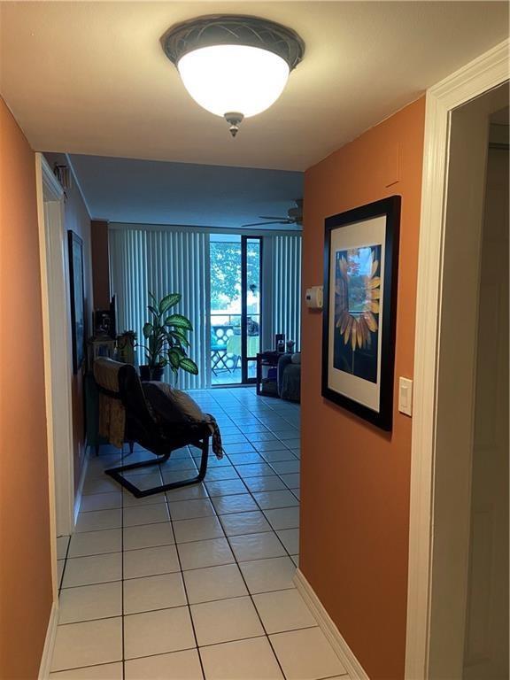A tiled hallway leads to a living area with a balcony view and a chair — 4222 Inverrary Boulevard # 4109, Lauderhill FL 33319, LAUDERHILL, FL