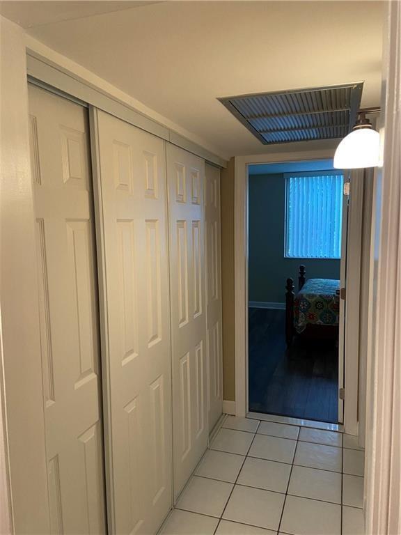 A hallway with white tile flooring and sliding closet doors leads into a bedroom — 4222 Inverrary Boulevard # 4109, Lauderhill FL 33319, LAUDERHILL, FL
