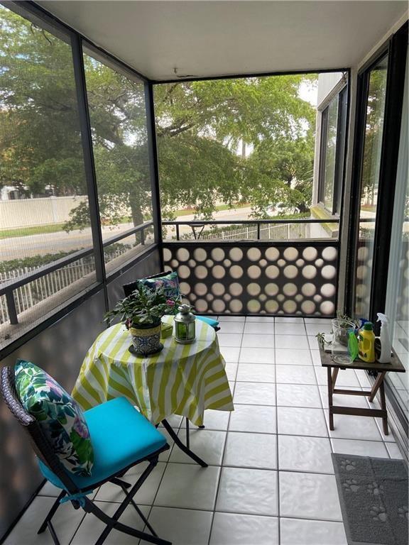 A screened-in balcony features white tile flooring, a small bistro table, and a decorative railing — 4222 Inverrary Boulevard # 4109, Lauderhill FL 33319, LAUDERHILL, FL