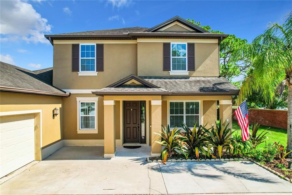 A two-story house with a tan stucco exterior, a covered entryway, and a concrete driveway — 421 MEADOWRIDGE COVE, LONGWOOD, FL