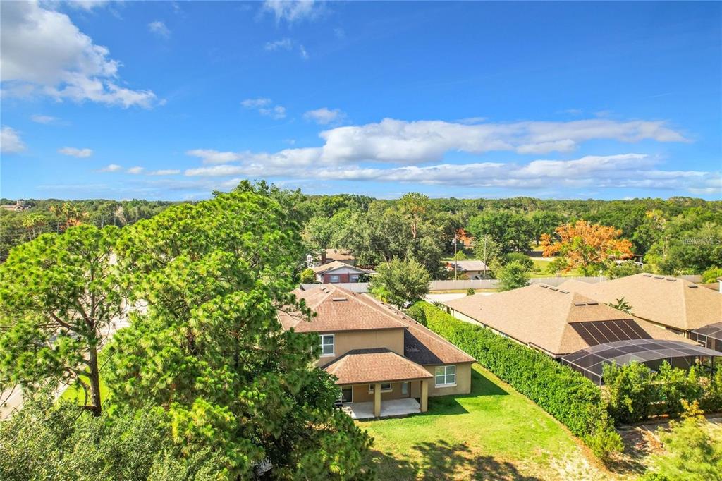 An aerial view shows a two-story house with a brown roof and a backyard lawn — 421 MEADOWRIDGE COVE, LONGWOOD, FL