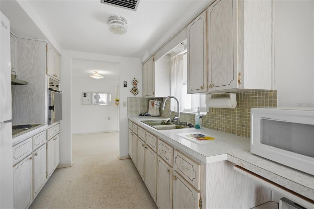 A kitchen features a green drop-in electric cooktop, a range hood, and light-colored cabinetry — 1207 LODESTAR DRIVE, HOLIDAY, FL