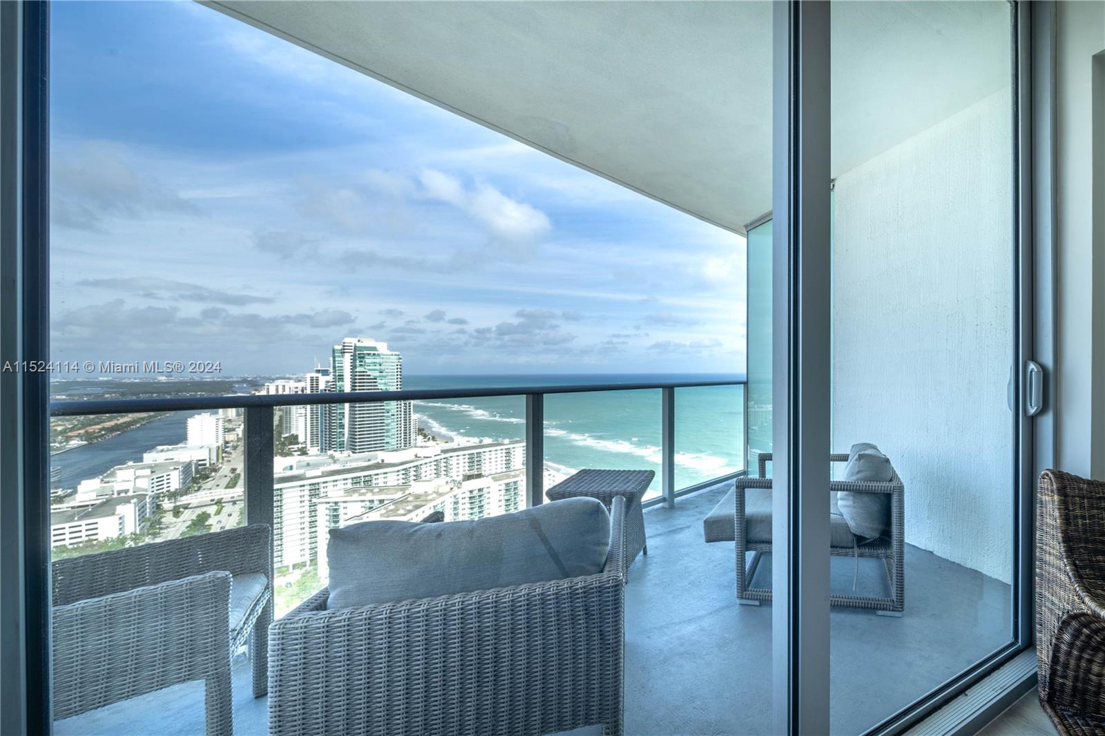 A high-rise balcony features wicker furniture overlooking the ocean and city skyline — 4111 S Ocean Dr # 3112, Hollywood FL 33019, HOLLYWOOD, FL