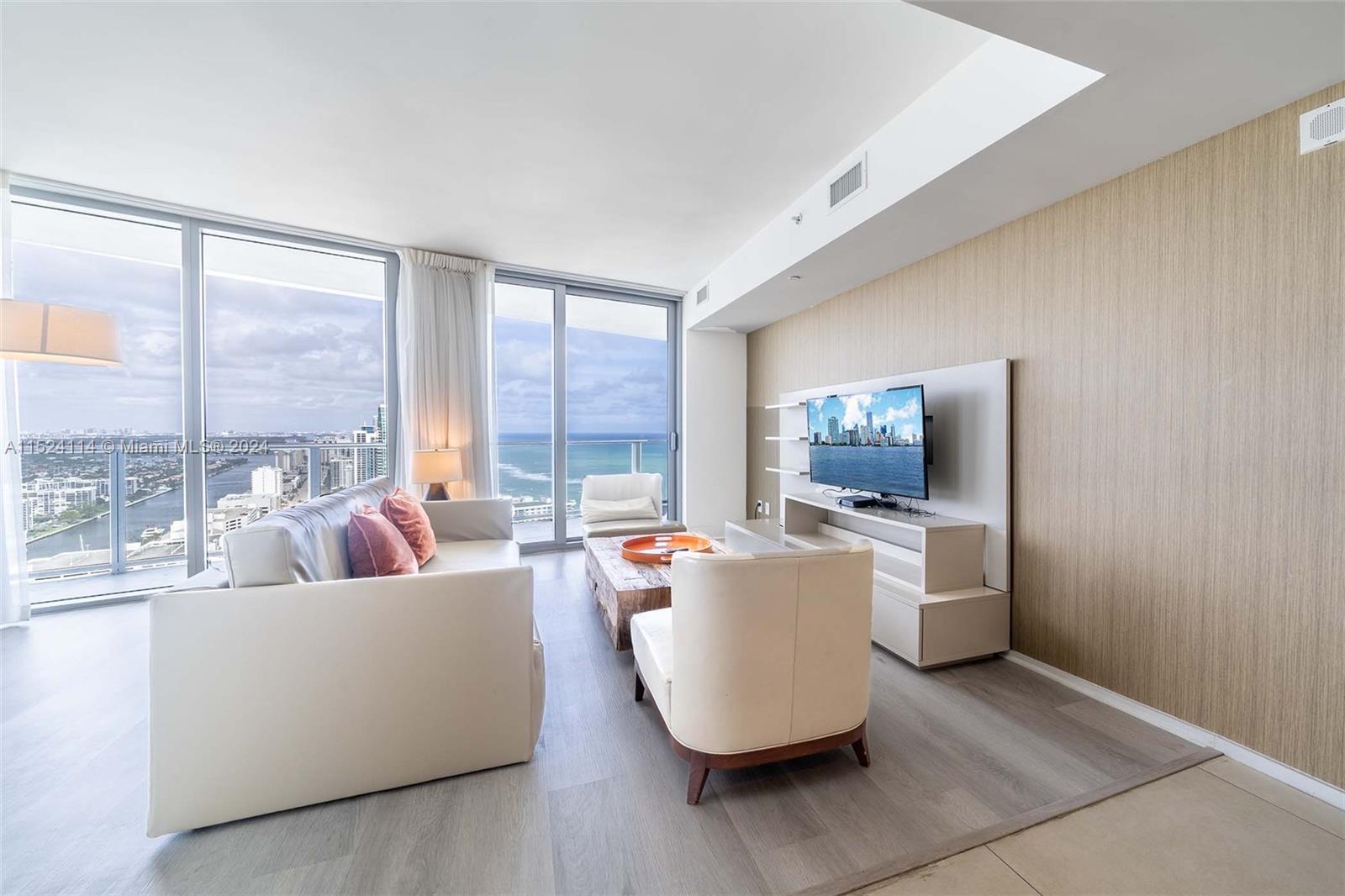A modern living room features white leather furniture, a wood coffee table, and ocean views — 4111 S Ocean Dr # 3112, Hollywood FL 33019, HOLLYWOOD, FL