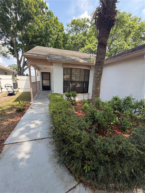 A concrete walkway leads to the front entrance of a house with a bay window — 692 BELLINGHAM PLACE, PALM HARBOR, FL