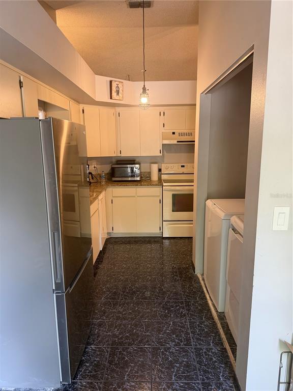 A kitchen with cream cabinets, a stainless steel refrigerator, and dark patterned tile flooring — 692 BELLINGHAM PLACE, PALM HARBOR, FL
