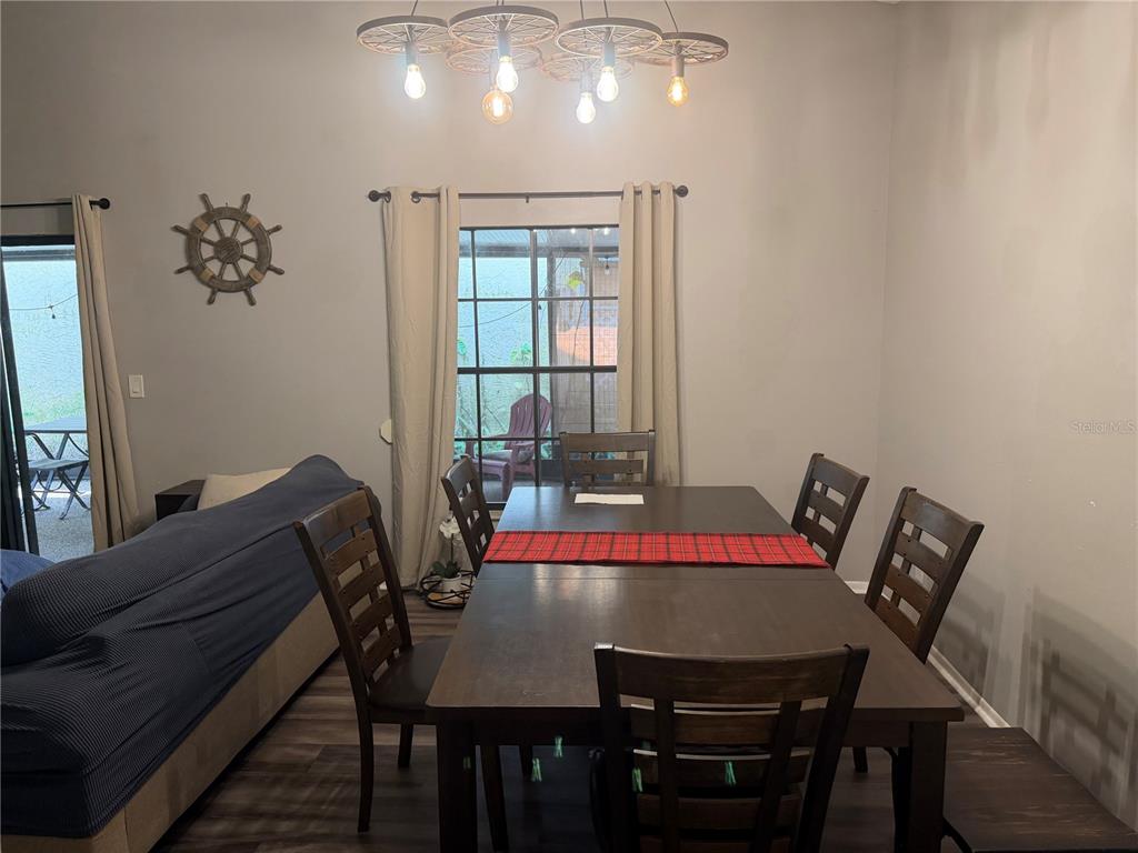 A dining room features a dark wood table, matching chairs, and a wagon wheel chandelier — 692 BELLINGHAM PLACE, PALM HARBOR, FL