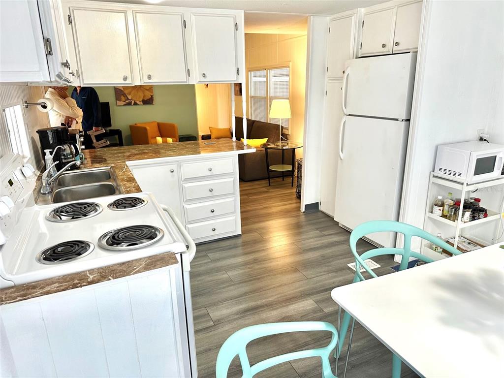 A kitchen with white cabinets, a brown countertop, and a view into the living room — 9790 66TH STREET N UNIT 194, PINELLAS PARK, FL