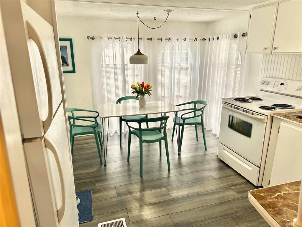 A kitchen and dining area with white cabinets, a white stove, and green chairs — 9790 66TH STREET N UNIT 194, PINELLAS PARK, FL