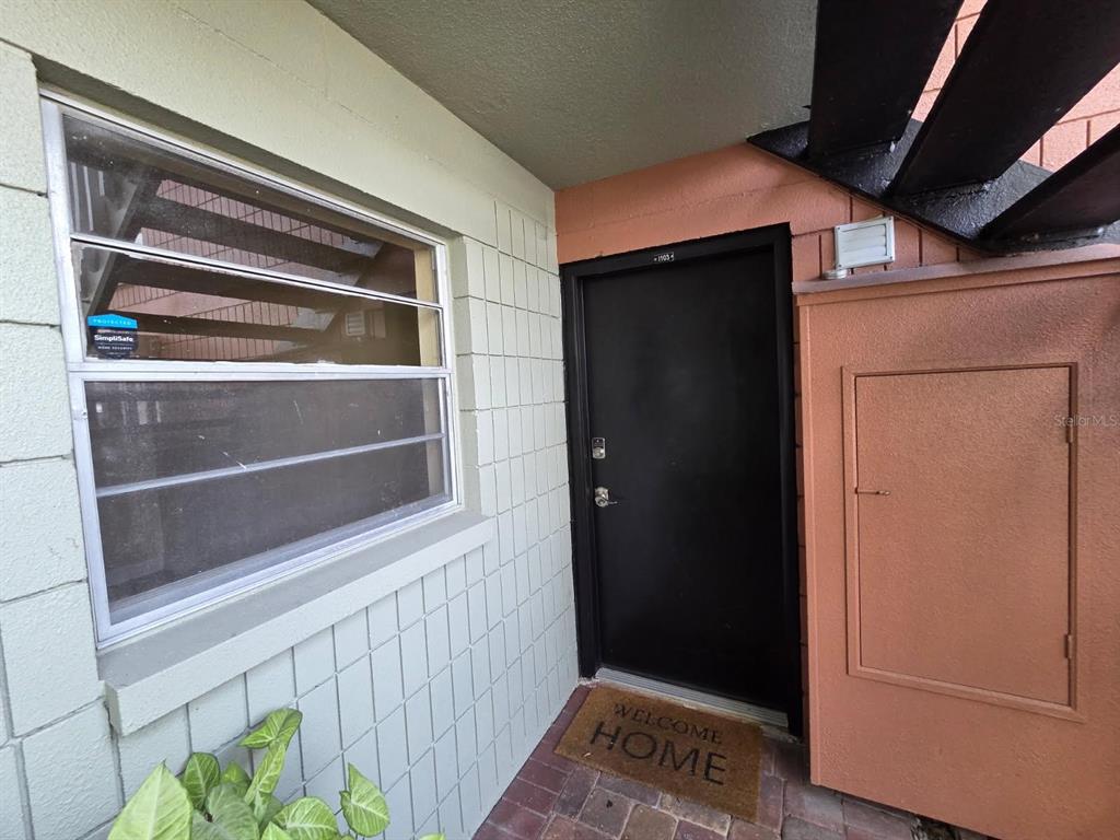 A black front door with a welcome mat sits beside a window and storage closet — 2424 W TAMPA BAY BOULEVARD UNIT I103, TAMPA, FL