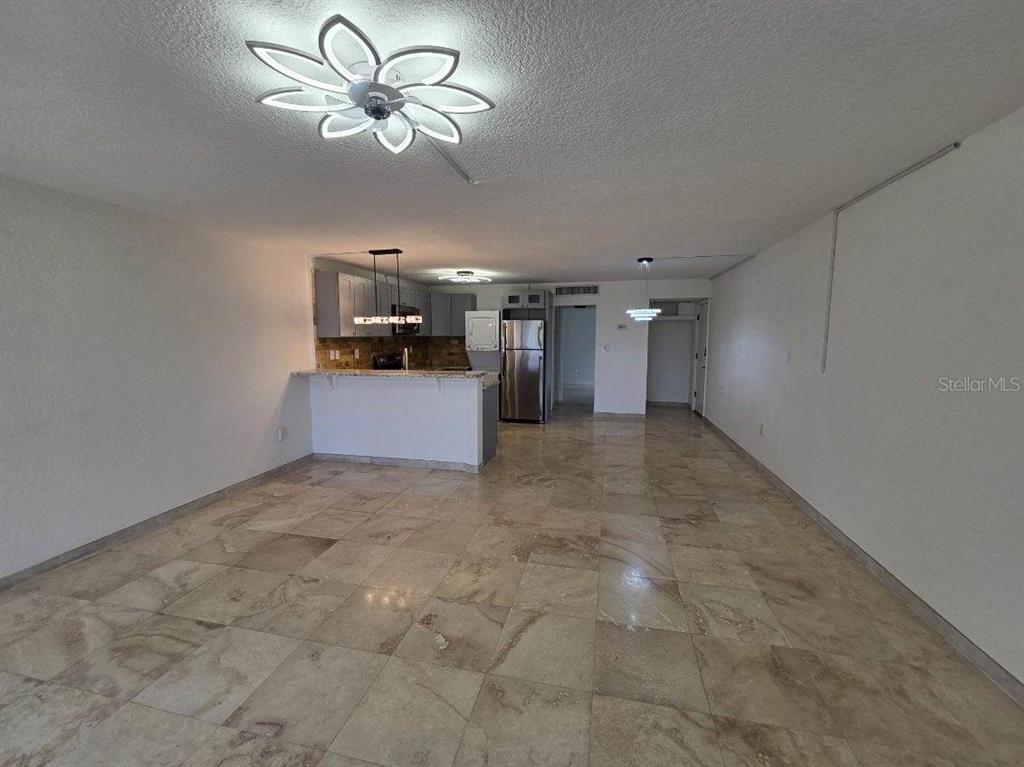 An open-concept living area features light-colored tile flooring, a kitchen island, and a ceiling light — 2424 W TAMPA BAY BOULEVARD UNIT I103, TAMPA, FL