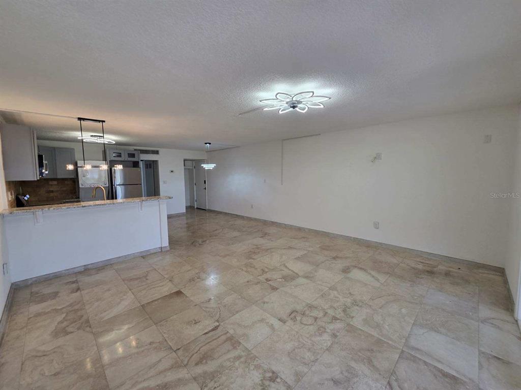 An open-concept living area features light-colored tile flooring and a kitchen with a breakfast bar — 2424 W TAMPA BAY BOULEVARD UNIT I103, TAMPA, FL