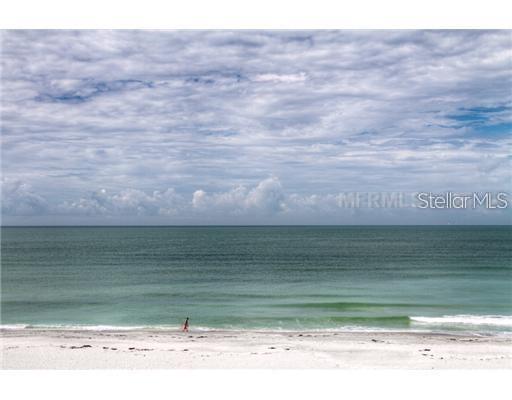 A lone person walks along a sandy beach by the ocean under a cloudy sky — 2425 GULF OF MEXICO DRIVE UNIT 4E, LONGBOAT KEY, FL