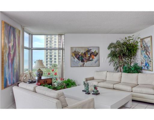 A living room features a white sectional sofa, a large coffee table, and floor-to-ceiling windows — 2425 GULF OF MEXICO DRIVE UNIT 4E, LONGBOAT KEY, FL